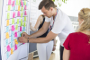 Mann klebt Post it auf Flipchart
